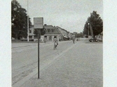 Torggatan skall stensättas. Artikel i samband med bilden publicerad i Varbergs Tidning 1958-08-29. I bakgrunden ses fastigheten Apotekaren 8. På gatan kommer en cyklist och vid torget står en skylt för busshållplats. Fastigheten Rådhuset 16 ser ut att vara under uppbyggnad.