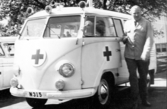 Bild från artikel i Hallandsposten 1963-06-01. Varbergsambulansen firar 10-årsjubileum, den startade 1 juni 1953. En man står bredvid ambulansen, som liknar en liten buss.