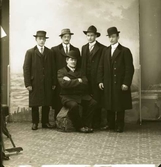 Ateljéfoto av fem män i hattar av olika typ, varav en med amerikanskt stuk. Beställare: J A Bernsson (Berntsson?) som troligen själv är med på fotot. Råfoto som är tänkt att beskäras.