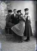 Syskonbild av tre systrar med hattar och en bror som står kring en balustrad. Beställare: Edit Karlsson. Troligen är bilden tagen i Björkströms Falkenbergsfilial. (Se även bildnr GB2_1617)