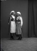 Ateljéfoto med två flickor i hembygdsdräkt, beställare:  Tekla Gustavsson.  Troligen är bilden tagen i Björkströms Falkenbergsfilial.
