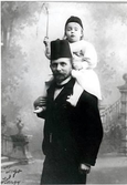 Porträtt av far och son. Hugo Gerlach, iklädd fez, bär sonen Harry på sina axlar. Harry, döpt efter sin morfar Harry Bagge, håller i en piska.