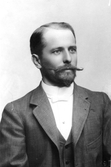 Porträtt av ingenjör Hugo Gerlach vid 47 års ålder. Mustaschen har antydning till knävelborrar och hakskägget är kort.