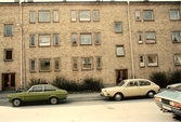 Bilar parkerade framför hyreshus på Norrgatan 27 A och 27B, 1982