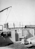 Man på tak i Förlunda i Hovsta tar emot byggdelar, 1986