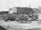 Grävmaskin lastar lastbil vid byggnation av Medborgarhuset, 1963-07-01