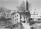 Ensamt rivningshus framför nybyggda hyreshus vid Drottninggatan, april 1962