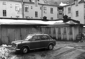 Bil parkerad vid förådsbyggnad på Karlslundsgatan 14, 1970-tal