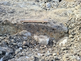 Sektion genom stolphålet AS213, som var flackt med stenskoning i botten. Foto mot väster. Från arkeologisk undersökning i form av schaktningsövervakning i Hede, Hälsingtuna socken, Hudiksvalls kommun.