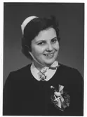 Bröstbild av Britt-Inger Johannesson, klädd i högtidsdräkt i samband med sjuksköterskeexamen vid Jönköpings läns landstings sjuksköterskeskola i december 1958.

Text på fotografiets baksida: 