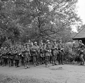 Soldater från Hälsinge Regemente, I 14, står uppradade på en väg
