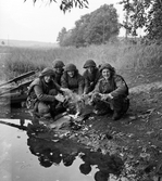 Fem soldater från Hälsinge Regemente, I 14, värmer sig vid en liten eld på stradskanten