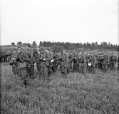 En grupp soldater från Hälsinge Regemente, I 14, ute på manöver. I framkant till vänster i bild står en fänrik med en kartväska.