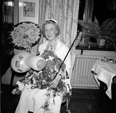 Kvinnlig student i hemmet poserar med blommor, ballong, parasoll och ridpiska