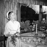 Kvinnlig student i hemmet poserar med sin ridpiska framför ett uppdukat fikabord