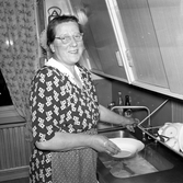 Äldrekvinna i köket tar hand om disken