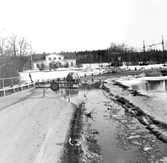 Bil kör förbi stoppskylt vid översvämning i Ervalla, 1977