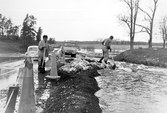 Vägarbetere försöker stoppa översvämning av väg i Vedevåg i Lindesberg, 1977