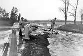 Vägarbetere försöker stoppa översvämning av väg i Vedevåg i Lindesberg, 1977