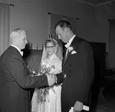 Bröllopsmiddag, brudgummen skakar hand med en man medan bruder ser på