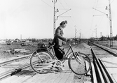 Kvinna med cykel vid övergång vid Gustavsvik, 1950-tal