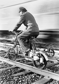 Banvakt på dressin vid sidan om rusande tåg, 1950-tal
