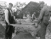 Utgrävning av Gamleby kyrkoruin i Varberg. (Getakärr). Två män sållar efter fynd och i bakgrunden går en man med skottkärra.
Tillhör samlingen med fotokopior från Hallands Nyheter som är från 1930-1940-talen.