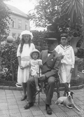 Familjebild i Mathilda Ranchs trädgård med handelsmannen Oscar Pehrson och hans barn Greta, Håkan och i knät Sven. Deras hund ligger vid Håkans fötter.