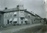 Ur byggmästare Johannes Nilssons fotoalbum från 1914. Vy från korsningen Bäckgatan-Östra Långgatan, kv Rådhuset. Huset uppfördes 1864 men renoverades av Nilsson. På det avfasade hörnet sitter en balkong över entrén och takterrassen med flaggstången på den låga torndelen kantas med ett smidesräcke.