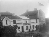 Mathilda Ranchs fotoateljé vid Prästgatan i Varberg. Tre personer står vid fasaden och i vinden vajar unionsflaggan, vilket påvisar att fotot togs före 1906. Ateljén byggdes 1890 om till detta utseende