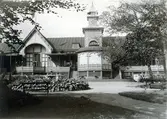Ur byggmästare Johannes Nilssons fotoalbum från 1914. Societetshuset i Varberg med en fontän omgiven av en funkiarabatt.