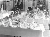 Utställning. Hemkulturutställningen i societetshuset (restaurangen) den 15-20/9 1931. Förslag på dukningar vid olika högtider. Framifrån räknat: 1: Silverbröllop, 2: Bröllop, 3: Guldbröllop. I bakgrunden Barres monter. Arrangör: Ernst Dyring. Glas och porslin från Linda Hansons.