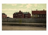Kolorerat vykort av Varberg gamla lasarett från 1901, sett från Prästgatan. Till vänster ses ekonomibyggnaden från 1904 och till höger läkarbostaden uppförd 1883.