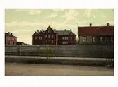 Kolorerat vykort av Varberg gamla lasarett från 1901, sett från Prästgatan. Till vänster ses ekonomibyggnaden från 1904 och till höger läkarbostaden uppförd 1883.