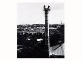 Två män högst uppe på skorstenen vid ekonomibyggnaden till gamla lasarettet i Varberg. Skorstenen tillkom troligen vid tillbyggnaden av lasarettet år 1921. I ekonomibyggnaden fanns både tvättstuga och kök. Bilden är tagen mot öster.