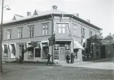 Ur byggmästare Johannes Nilssons fotoalbum från 1914. John Victorins guldsmedsaffär på hörnan av Norrgatan-Kungsgatan i kv Berget. Byggnaden uppfördes 1831. Victorin startade här sin verksamhet 1908 och den finns kvar än idag (2023). På Kungsgatan ligger John Antonson Dybergs speceriaffär.