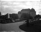 Man vilar i parksoffa i Centralparken vid statyn Befriaren mitt emot Örebro slott, 1920-tal