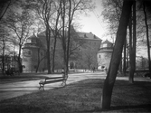 En ensam trädgårdssoffa i Slottsparken med utsikt mot Örebro slott, 1930-tal