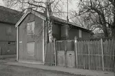 Ett bostadshus med lockläcktpanel och igenbommade fönster. Staket till höger bredvid huset på Strandgatan.