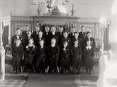 Konfirmandgrupp år 1939 med prästen vid altarringen i Valinge kyrka med altarskranket i bakgrunden.