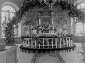 Interiörbild av Horreds kyrka. Koret med altarring och altaruppsats sett genom en lövad ärebåge. Korväggen har kvadermålning.