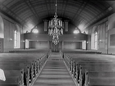 Interiörbild, troligen Tvååkers kyrka från omkring 1930, (restaurerades då). Vy från koret över bänkkvarteren mot orgelläktaren som har runda gavelfönster. Det välvda taket är dekormålat med rutor. Altargång, läktare med orgel.