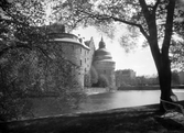 Örebro slott sett genom trädgrenar i centralparken, 1930-tal