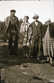 Bygdefotografen Erik till vänster med Britta, Julius och Alma på en Berghäll utei naturen. Julius ser ut att hålla en tubkikare i ena handen och en käpp i den andra.