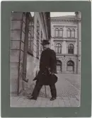 En man med portfölj under armen promenerar över Stora torget, kvarteret Kransen, Uppsala