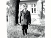 Porträtt av pojken Karl Hugo Svensson fotograferad utomhus. I bakgrunden syns en husfasad.