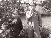 Barnen Karl Hugo Svensson och Maj Johansson äter frukt i trädgården. De var fosterbarn hos 