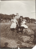 Familjen Gustafsson sitter på några stenar framför ängarna vid Kållered Stom 1:3 