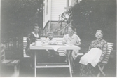 Fyra personer sitter och fikar i trädgården utanför 