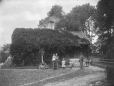 Bostadshus, familjegrupp fem personer framför huset. 
Ernst Ringström, Myrö, Rinkaby socken.